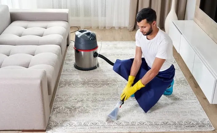 A technician cleaning a patterned rug with a hot-water extraction wand